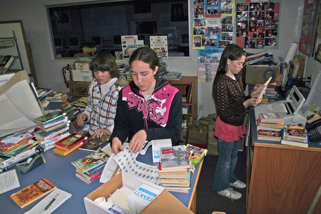 From left, eighth grader Ryan Medlin, eighth grader Tiffany Marshall and seventh grader Erica Phillips work in the Grenada Elementary School library on Thursday. To save funds, the school did not renew its book contract with the county office of education, and is asking the community for help with making sure shelves are re-stocked for the upcoming school year.