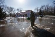 Verne Parks of the Minnesota National Guard from Bemidji, Minn., wades through the water to bring supplies to home owners fighting the Red River flooding in Oakport, Minn. on Saturday, March 28, 2009,