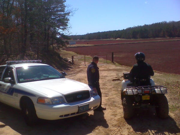Falmouth police officers restrict access to an East Famouth cranberry bog on Carriage Shop Road today. Skeletal remains were found on the bog on Saturday. Investigators returned to the bog today for further investigation, which may include the discovery of more bones.
