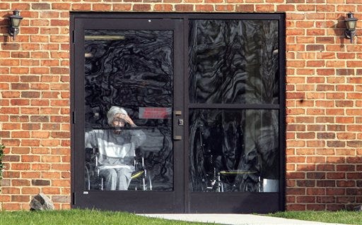 A resident peers out a door at Pinelake Health and Rehab Center in Carthage, N.C., Monday, March 30, 2009, a day after seven residents and one staff member were shot and killed. (AP Photo/Jim R. Bounds)