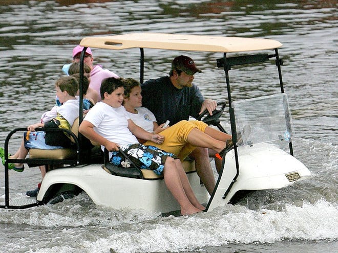 People cross a flooded street in a golf cart on their way to the beach on Thursday, April 2, 2009 in Panama City Beach, Fla.