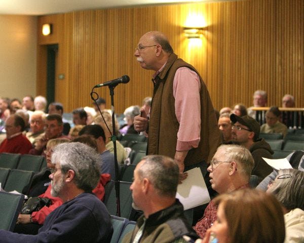 Kingston resident John Haas steps to the microphone to ask questions about expenditures, ownership, and maintenance of property during Saturday's annual town meeting at the Kingston Intermediate School.