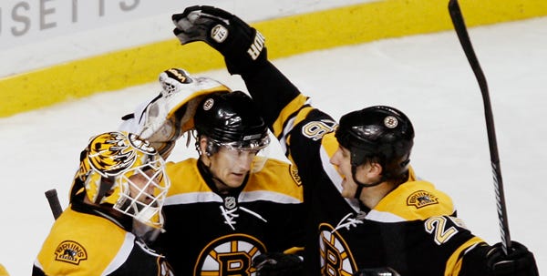 Bruins goalie Tim Thomas, left, joins teammates P.J. Axelsson, center, and Blake Wheeler after defeating the New York Rangers 1-0 to win the Eastern Conference regular-season title Saturday at TD Banknorth Garden. Thomas made 31 saves and Wheeler scored the game’s lone goal in the first period.