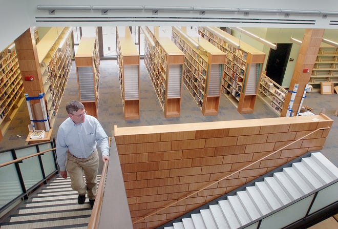 Library Director Philip McNulty climbs a stairway that leads to an upper balcony in the new wing of the town library.