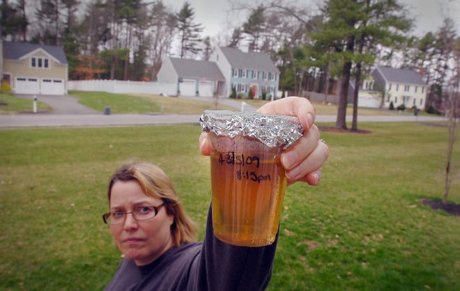Sue Foley holds a glass of water drawn from a faucet in her Wildwood Road home on April 5. The water is yellowish brown and contains sediment. Foley says she has contacted the town's health and water departments about the problem and that they have told her the water is safe to drink. Foley said she asked a water department employee to come to her home recently to drink the water, and that he came to the house, declined to drink the water, but told her the water was safe for her two children, ages 5 and 6, to drink. Foley says the problem of brown water has recurred many times in their Wildwood Road neighborhood since they moved there in 2004.