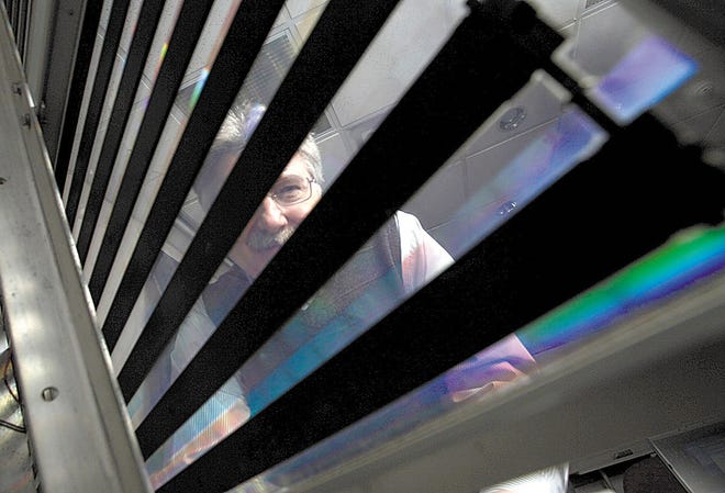 Rick Lewandowski of Stone Ridge, president and CEO of Prism Solar Technologies, looks through a solar panel that uses his patented film that focuses the sun's rays to the darker silicon solar cells.