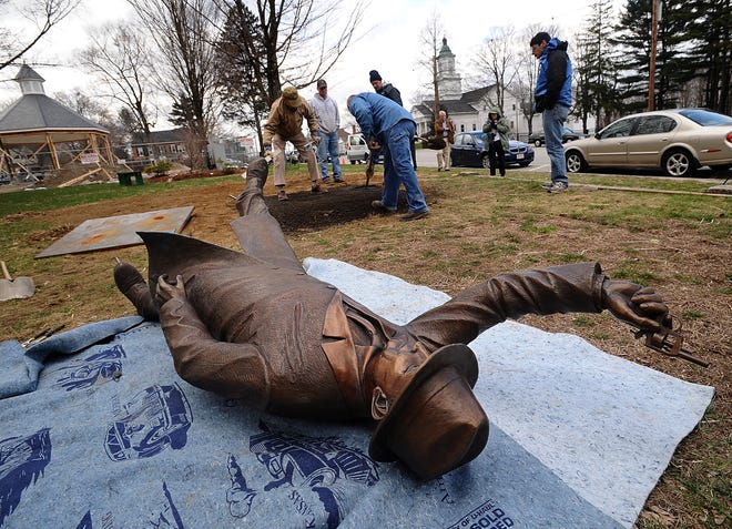 Workers (in the background) rake the foundation during the installation of the statue "The Starter" on Hopkinton Common Wednesday. The piece was made by Hopkinton sculptor Michael Alfano and honors George V. Brown, the Boston Marathon starter from 1905 to 1937.