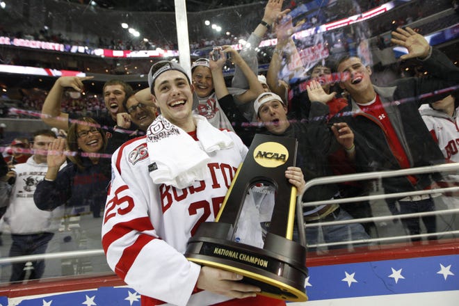 Boston University's Colby Cohen holds the championship trophy after the Terriers beat Miami (Ohio) in overtime to win the NCAA title game, 4-3.