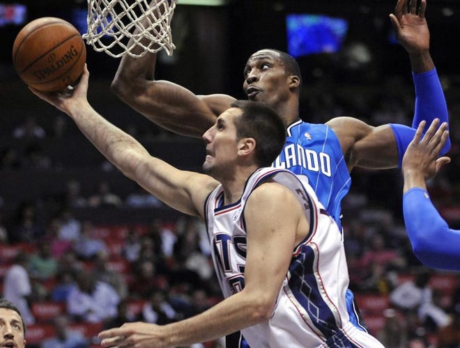 New Jersey Nets' Ryan Anderson puts up a shot as he gets by Orlando Magic center Dwight Howard, rear, during the first quarter of an NBA basketball game Saturday in East Rutherford, N.J.