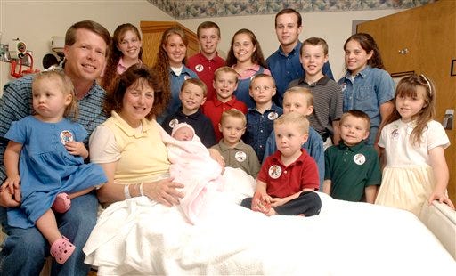 FILE -- In this Aug. 2, 2007 file photo, Michelle Duggar, left, is surrounded by her children and husband Jim Bob, second from left, after the birth of her 17th child in Rogers, Ark. (AP Photo/ Beth Hall, File)