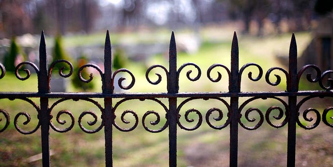 An ornate wrought iron fence guards the entrance to a graveyard on Mann Lot Road in Scituate.