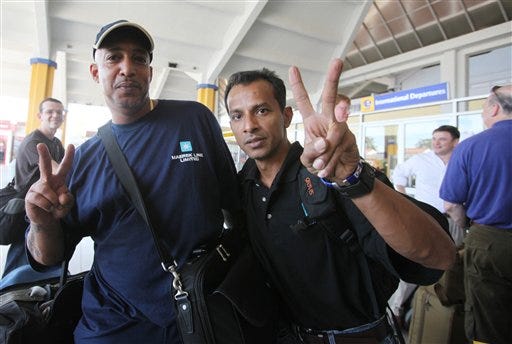 Crew members of the merchant vessel, Maersk Alabama, which was confronted by Somali pirates, wave victory signs as they wait at the international airport at Mombasa, Kenya, Wednesday, April 15, 2009. The crew of the U.S. freighter that thwarted a pirate attack are at Mombasa airport preparing to return home, according to Maersk shipping line officials. Their captain, Richard Phillips, who remained with the pirates was rescued by U.S. Navy SEALs Sunday, April 12, 2009.(AP Photo/Sayyid Azim)