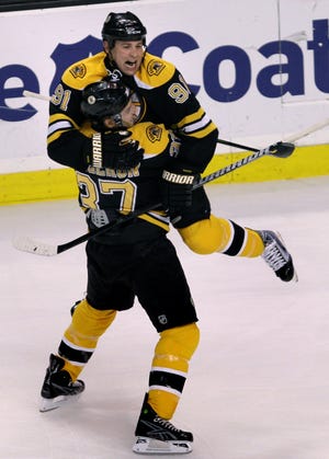 Bruins center Marc Savard (91) leaps into the arms of teammate Patrice Bergeron after scoring the first goal of the game against Montreal Canadiens.