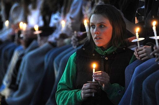 Jen Beaver, 23, holds her candle as she watches the candlelight vigil at the Columbine Memorial at Clement Park near Littleton, Colo., on Sunday, April 19, 2009.