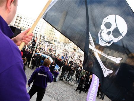 One of the hundreds of supporters of file-sharing hub The Pirate Bay that demonstrated in Stockholm, Sweden on Saturday April 18 2009, waves a Jolly Roger, pirate flag while Sweden's Pirate Party chairman and founder Rickard Falkvinge talks in the background. Four men were sentenced Friday to one year in prison each for helping millions of Pirate Bay users commit copyright violations of movies, music and computer games. The court also ordered them to pay 30 million kronor ($3.6 million) in damages to international entertainment companies.