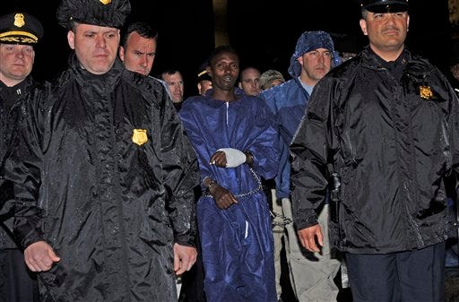 Police and FBI agents escort the Somali pirate suspect U.S. officials identified as Abduhl Wali-i-Musi into FBI headquarters in New York on Monday, April 20, 2009. Abduhl Wal-i-Musi is the sole surviving Somali pirate suspect from the hostage-taking of commercial ship captain Richard Phillips from the Maersk Alabama. (AP Photo/Louis Lanzano)
