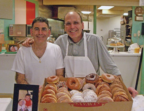Bob, left, and Mike George stand behind the counter of Colonial Do-Nut Shop with a box of fresh doughnuts.
