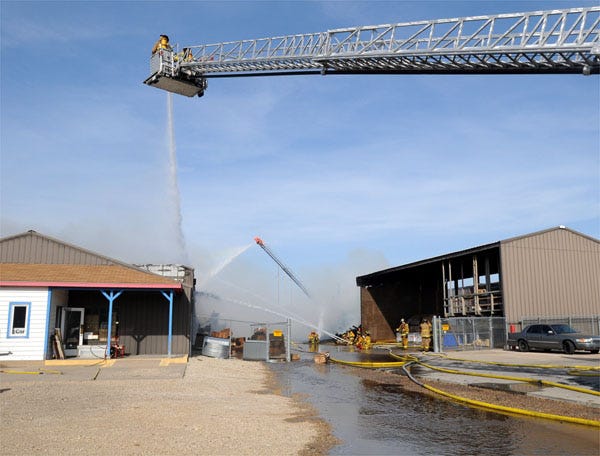 Fire crews with the Manhattan Fire Department use aerial platforms Friday afternoon to battle an intense blaze at Griffith Lumber Company, 820 Levee Drive.