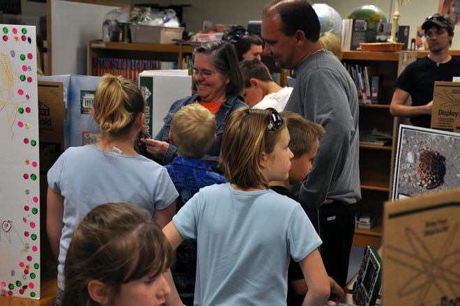 Gier families look over science fair projects with their kids in the Gier Elementary School library.