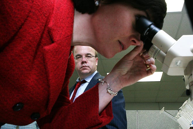 U.S. Rep. James McGovern watches as state Rep. Carolyn Dykema uses a microscope to examine a filter manufactured by Rypos Inc., a Holliston company that specializes in clean air technology.
