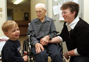 Kathy Holste, right, holds her father Warren Reuber’s hand as they both smile at Holste’s son Jacob, who was entertaining them at Stephenson Nursing Center in Freeport. Reuber is a resident at the nursing center and is under FHN Hospice care.