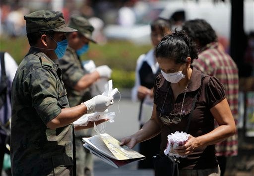 Soldiers pass out surgical masks in Mexico City, Saturday, April 25, 2009. (AP Photo/Gregory Bull)