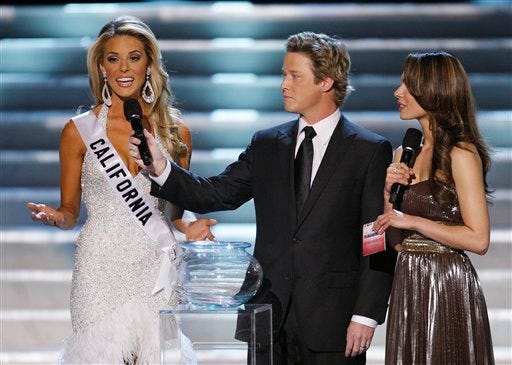 Hosts Billy Bush, center, and Nadine Velazquez, right, listen as Miss California Carrie Prejean, left answers a question from judge Perez Hilton, unseen, about legalizing same-sex marriage during the Miss USA Pageant, April 19 in Las Vegas. "We live in a land where you can choose same-sex marriage or opposite marriage," Prejean said. "And you know what, I think in my country, in my family, I think that I believe that a marriage should be between a man and a woman. No offense to anybody out there, but that's how I was raised."