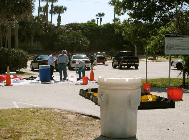 DAN SCANLAN/StaffHazardous material cleanup crew members gather contaminated items Friday morning at the Mickler's Landing beach parking lot, the site of the sodium cyanide exposure.