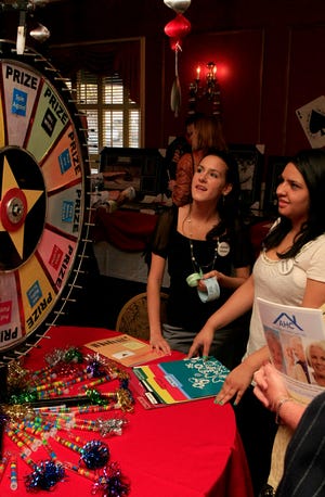 Danvers High School sophomores Christina Glavin and Crystal Chanlatte (L to R) help out at the prize wheel during the North Shore Elder Services "Whodunit" Clue-themed fundraiser at the Hawthrone Hotel in Salem on Thursday night, April 30.