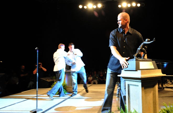 BRUCE LIPSKY/The Times-UnionDanny Wuerffel places Tim Tebow's Heisman Trophy on a pedestal while comedian Kenn Kington (background left) and Tebow celebrate their faith at the Night of Champions revival on Friday.