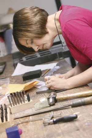 Kristen Ramsey, a full-time mom and a part-time jewelry artist, works on a sterling silver custom necklace for a client in the basement workshop of her Massillon home.