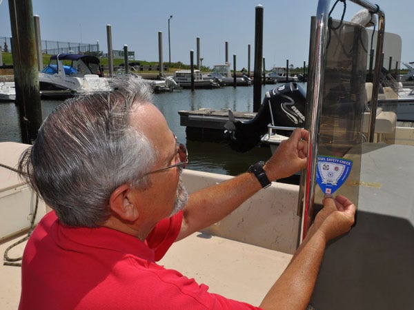 Lt. Mike Nevin, a vessel examiner with the Cape Fear Sail and Power Squadron, affixes a decal to a boat's windshield certifying that it passed a safety inspection.