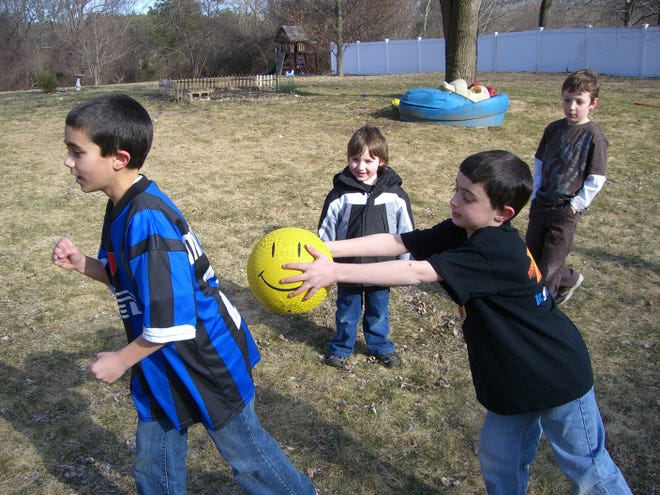 Nicolas Zonghi, 9, of Natick, tries to tag out his brother, Joseph, 12, with a ball while recreating the game he invented for a contest sponsored by Goldfish Crackers. Behind him are cousins Sam Carr, 4, and Ben Carr, 7.