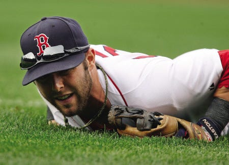 Red Sox second baseman Dustin Pedroia lies on the grass after attempting to field a cutoff throw during the sixth inning of Saturday’s game in Boston.