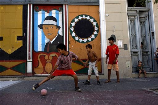 Children play in front of a painting of Carlos Gardel in Buenos Aires, Friday, Feb. 27, 2009. Gardel is considered world's most famous tango singer and composer. Argentina and Uruguay have been in a spat over this birthplace since he died in 1935 but now both countries have kicked aside a long-standing feud over tango's greatest icon and linked arms to persuade the United Nations cultural organization to give the world-famous dance and music protected status.