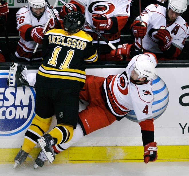 Boston Bruins' left wing P.J. Axelsson (11) slams Carolina Hurricanes defenseman Dennis Seidenberg (4) against the boards in the third period during Game 7 of an NHL hockey Eastern Conference semifinal series, Thursday, May 14, 2009, in Boston. (AP Photo/Charles Krupa)