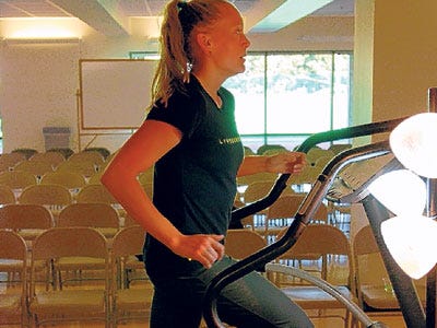 Fitness instructor Alicia Swift demonstrates a specially equipped elliptical machine that generates electricity recently at the University of Oregon in Eugene, Ore.