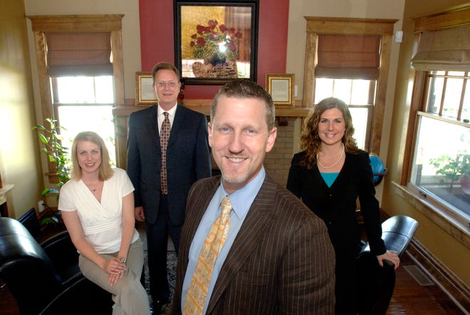 Chris Monroe, foreground, and his wife, Heather, along with staffers Erin Lard and Tim Rollet, stand in the office of CPS, 4211 N. Prospect Road, Peoria Heights. The financial services company started by the Monroes offers ways their clients can minimize their financial risks during an economic downturn.