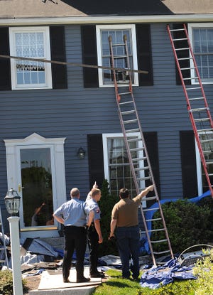 Police talk to an investigator after a scaffolding collapse at 5 Claybrook Farm Road in Medway this morning. Three workers from Bob Rogers Roofing were taken from the scene, one by rescue helicopter. (Daily News photo by Ken McGagh)