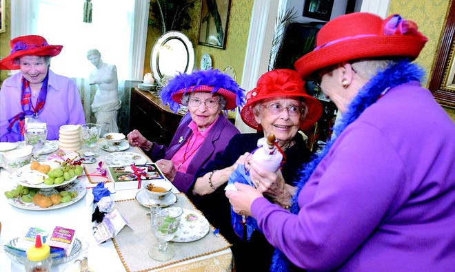 Jo Pancione, right, hands a raffle prize to Marion Cosmano during a tea party held by the Brighton Mad Hatters group at the Valentown Museum. Looking on are Bernice Blake, left, and Kay Kowba.