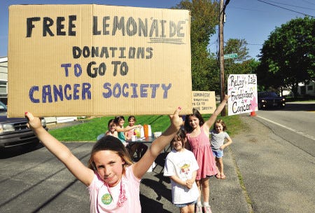 Ruby Hardy-Miller 8, of Portsmouth, front, holds a sign for free "lemonaide" outside a stand at 328 Ocean Road in Portsmouth in order to raise money through donations for the Cancer Society. Her friends include from left seated, Brianna Sullivan, 10; Natalie Cartaboua, 10; Maeve Riley, 7; Madeline Dubosque, 5; Tabitha Dubosque, 7; Anya Bakon, 5; and Anthony Yevdokimov, 9, hidden with back sign.
