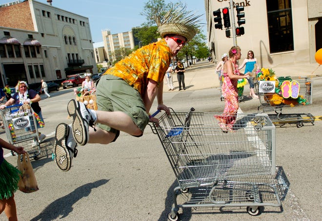 A reveler with the Kroger group goes airborne with the help of his shopping cart during Friday's Louie Louie parade in Downtown Peoria.