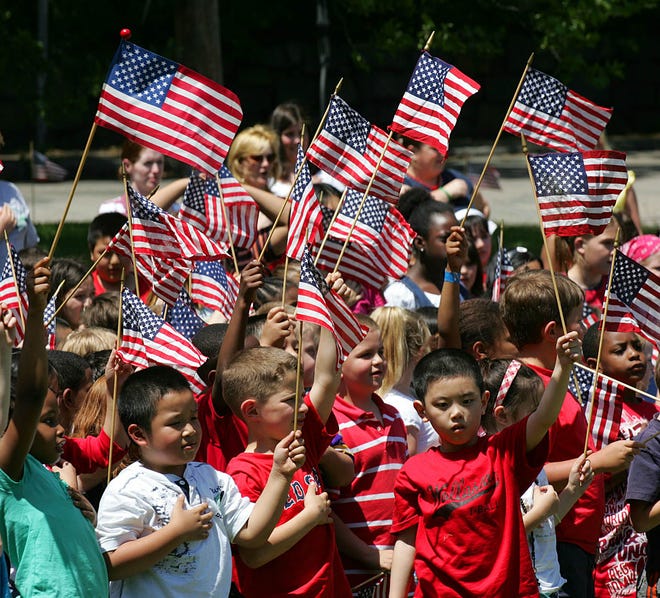 Students from the Lincoln-Hancock School in Quincy wave flags during the ceremonial planting of a lilac bush to finish the school's beautification project. Students also sang "America the Beautiful" after the planting.