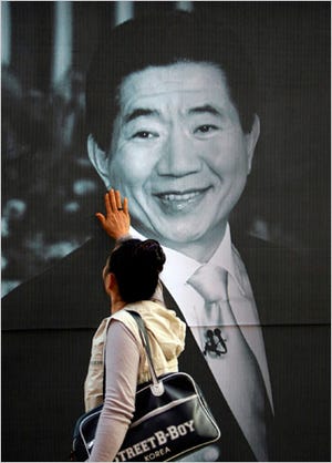 A South Korean woman touches a portrait of former President Roh Moo-hyun at Jogye temple in Seoul, South Korea, on Sunday.