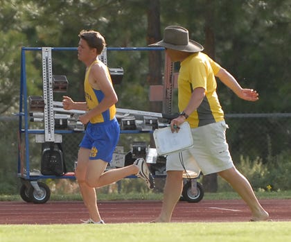 Mitchell Nesheim gets encouragement from his coach and father Steve as he begins the final lap of his victorious 3200 meter run Friday at the Division 3 Championship meet May 22 at College of the Siskiyous in Weed.