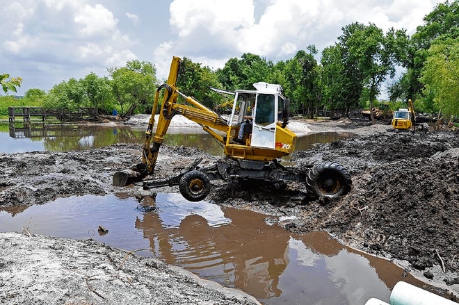 Crews with Stan Cisilski Inc. work a Menzi Muck machine into position to remove muck from the Lake Howard shoreline across from South Lake Howard Nature Park Wednesday afternoon. Wednesday, May 27, 2009.