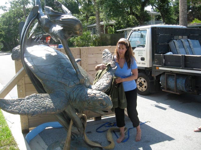 DREW DIXON/StaffDelaware sculptor Kristen Visbal polishes her creation, "In Search for Atlantis." The sculpture was hoisted into place at the five points intersection in Atlantic Beach on Wednesday.