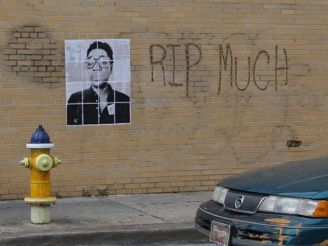 A Gainesville man was arrested for pasting this poster of his late friend and spray painting "RIP Much" on the side of a downtown building. Charged were later dropped.