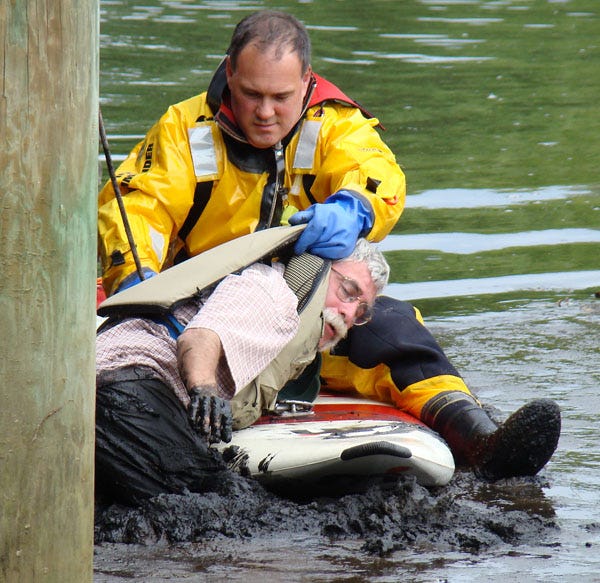 Man stuck waist-deep in the mud off Chase Road in Harwich is pulled onto a rescue surfboard yesterday.