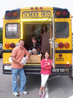 Helping to stuff buses with boxes of food during Monday's second annual Stuff-a-Bus food drive are, from left, David Friess, Samantha Vaccaro and Emily Friess.